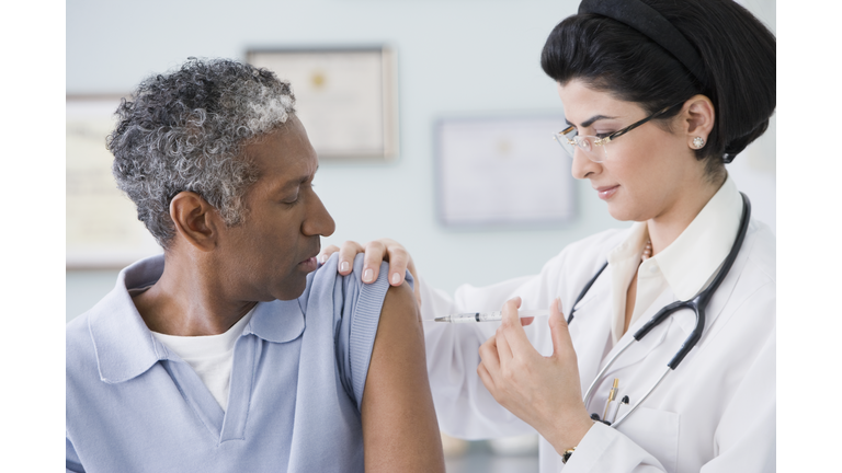 Middle Eastern female doctor giving shot to patient