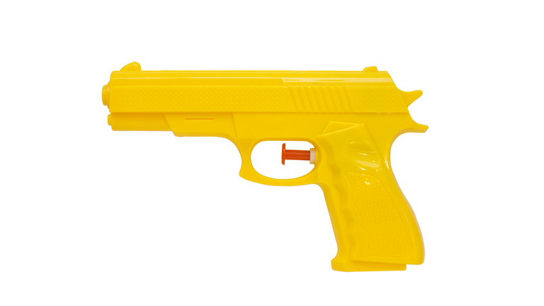 Close-Up Of Yellow Squirt Gun Against White Background