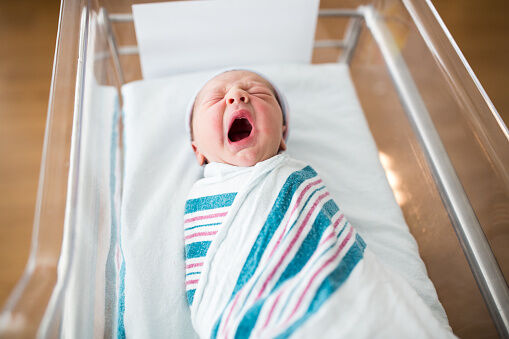 Newborn Infant Yawning in Crib