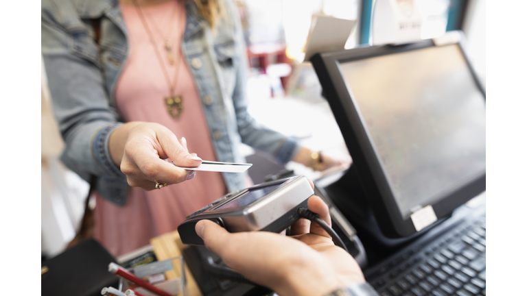 Female shopper paying with contactless credit card in shop