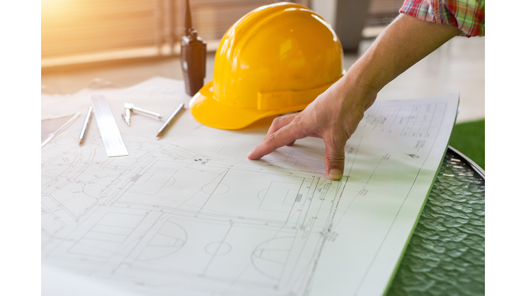 Architect engineer and head constructor working on a building site holding a blueprints at construction site.