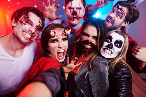 Friends in creepy costumes having fun at Halloween party