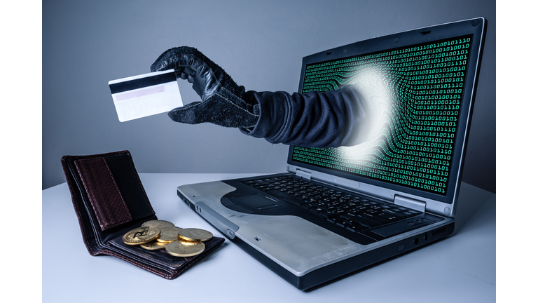 The abstract image of the hacker's hand reach through a laptop screen for stealing credit card in a wallet. the concept of cyber attack, virus, malware, illegally and cyber security.