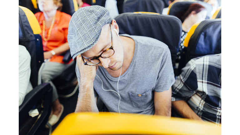 Businessman listening music while sleeping in airplane