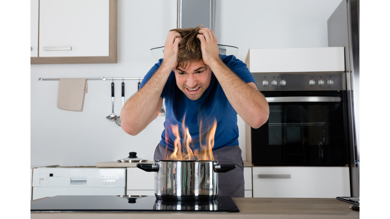 Young Male Looking At Cooking Pan On Fire