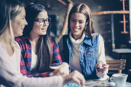 Three cheerful  girls playing board game.