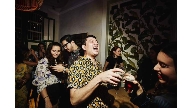 Laughing friends toasting during party in night club