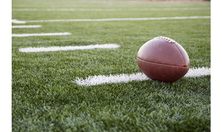 Close up of American football ball on green playing field