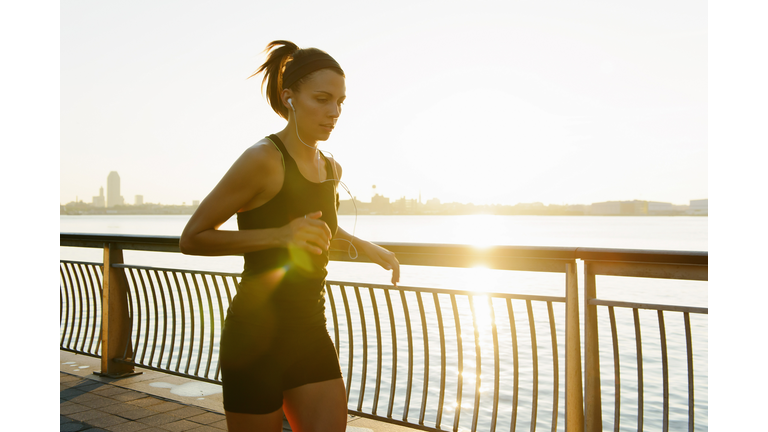 Young female jogger running at sunrise