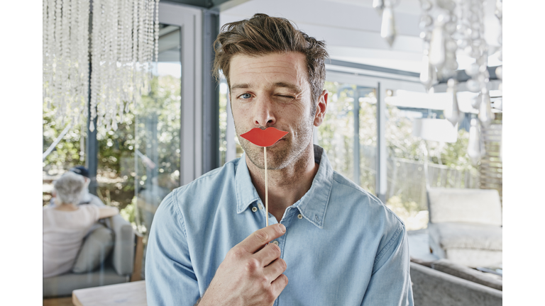 Man holding paper lips in front of his mouth