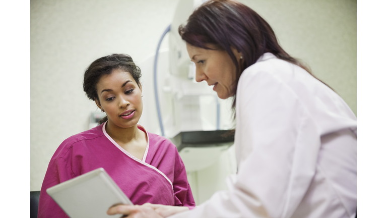 Mature doctor using digital tablet to explain to female patient