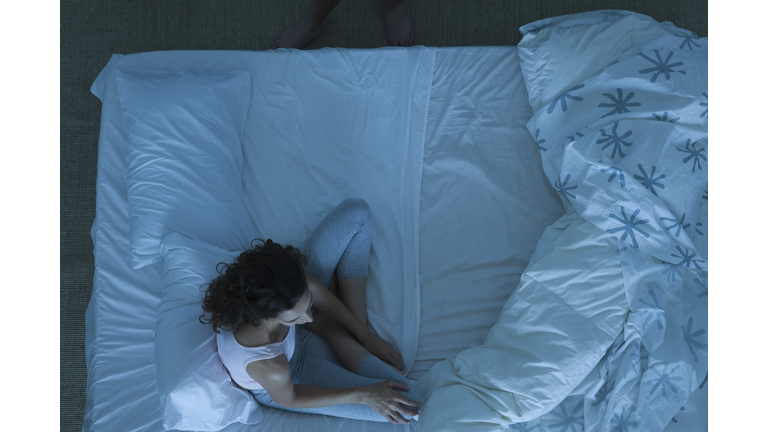 Couple in conflict, woman sitting on bed looking away