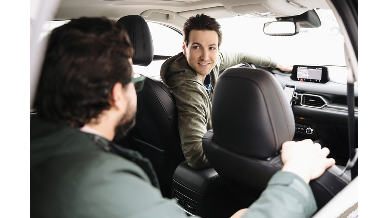 Male crowdsourced taxi driver talking with passenger in car