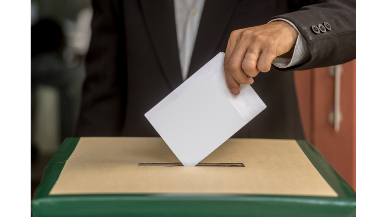 Hand of a person casting a vote into the ballot box during elections