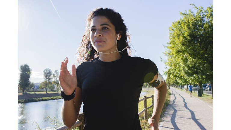 Sportive young woman running at the riverside