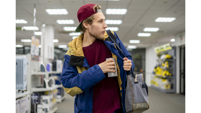 shoplifter in the electronic store supermarket stealing new gadget f