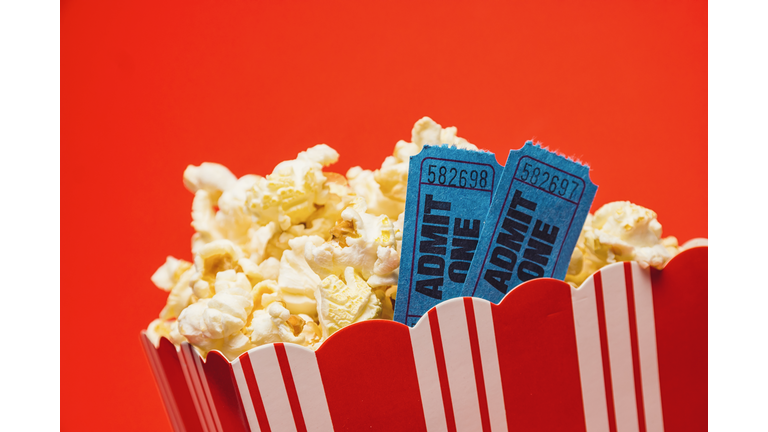 Popcorn And Movie Tickets With Numbers In Container Against Red Background