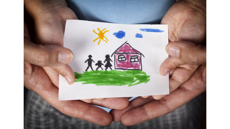 Child and his mom holding a drawn house with family