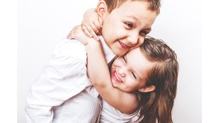 Toddler siblings hugging studio portrait