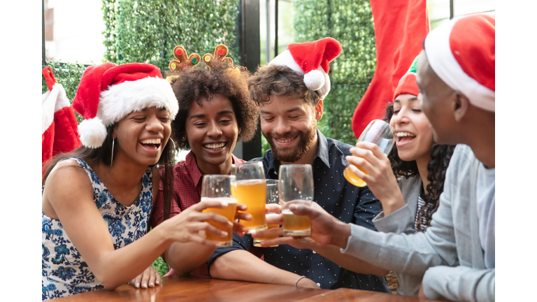 Diverse group of friends celebrating christmas at a bar drinking beer having fun