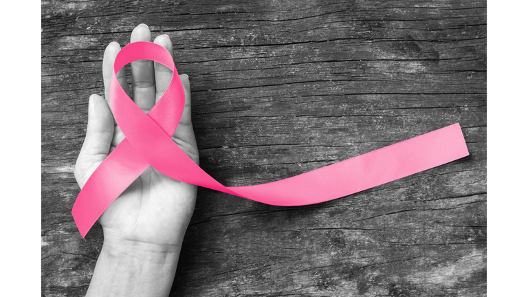 Pink ribbon awareness symbol on woman hand: Symbolic logo icon concept raising awareness campaign on female people living with breast cancer