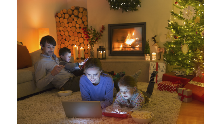 Family relaxing, using laptop, digital tablet and cell phone in ambient Christmas living room