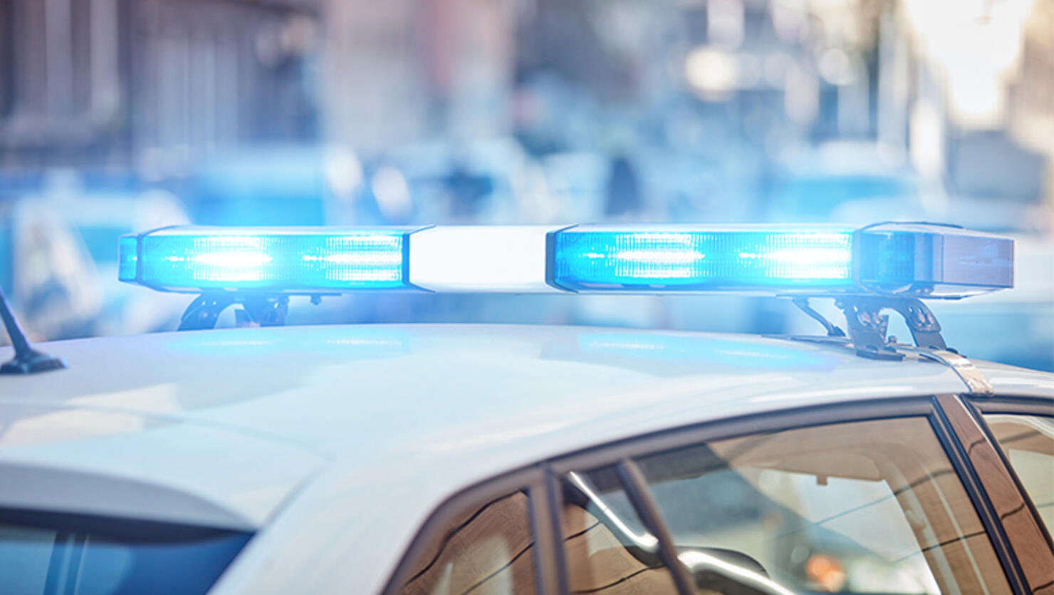 Police car with blue lights on the crime scene in traffic / urban environment.