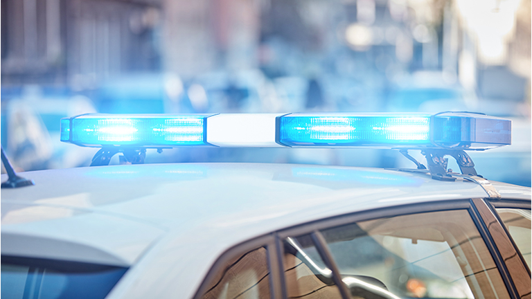 Police car with blue lights on the crime scene in traffic / urban environment.