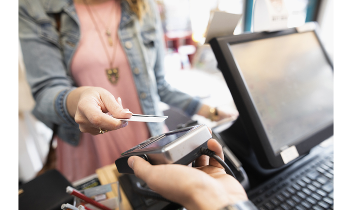 Female shopper paying with contactless credit card in shop