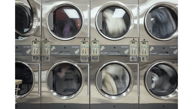 Laundry drying, spinning in clothes dryer at laundromat