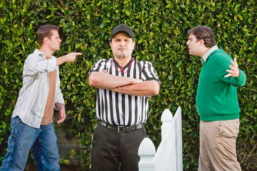 Hispanic referee between arguing neighbors