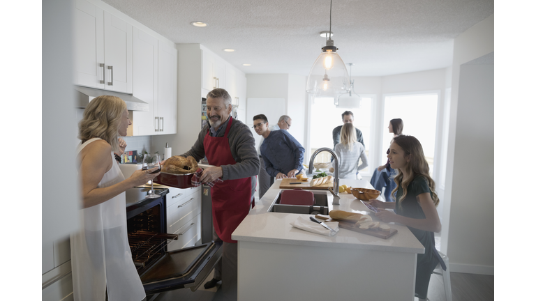 Multi-generation family preparing Christmas turkey in kitchen