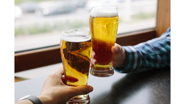 Close up of two men's hands holding beer glasses