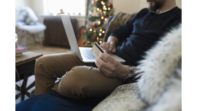 Young man with credit card online Christmas shopping on laptop