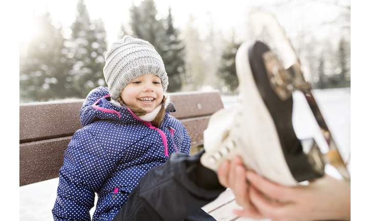 Mother helping daughter to put on her ice skates