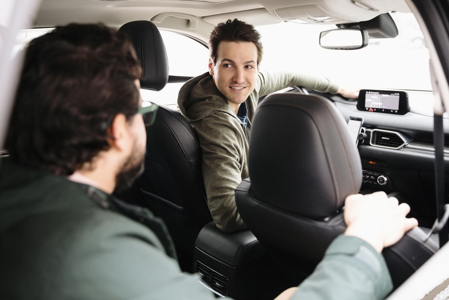 Male crowdsourced taxi driver talking with passenger in car