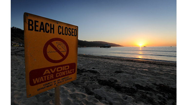 A beach closed sign warns against contam