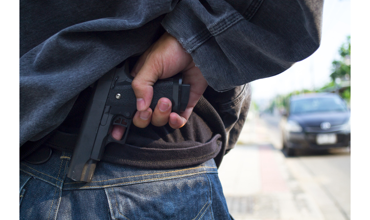 Robber holding a gun at abandoned building. Low key photo and selective focus. criminality concept.