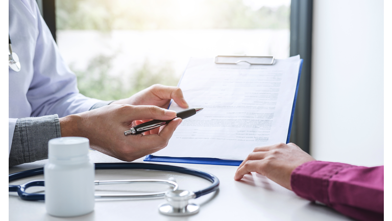 Midsection Of Doctor Showing Insurance Form To Patient