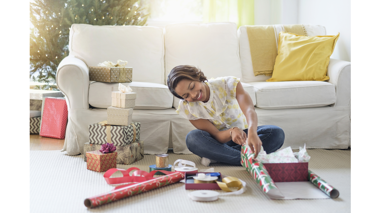 Black woman sitting on floor wrapping gifts