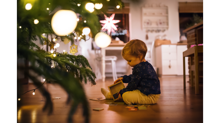 A small girl playing indoors on the floor at Christmas time.