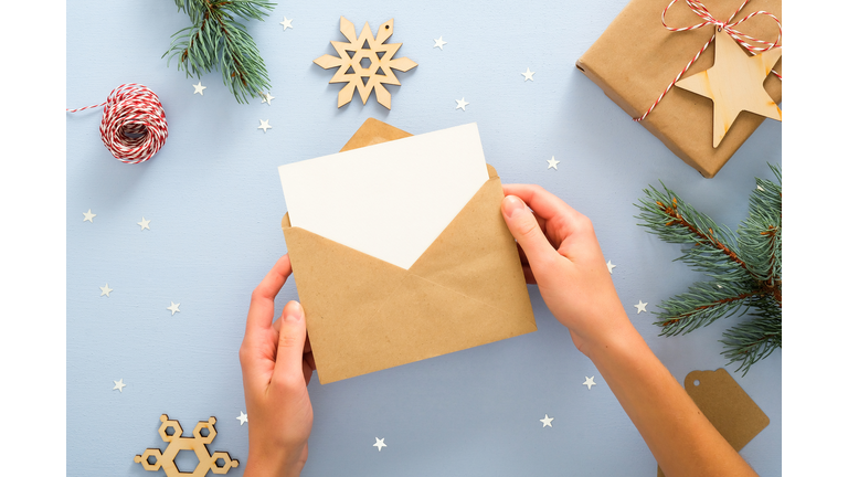 Cropped Hand Of Woman With Christmas Card In Envelope At Table