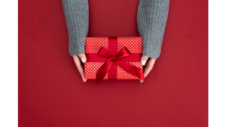 gift in female hands on a colored background top view.
