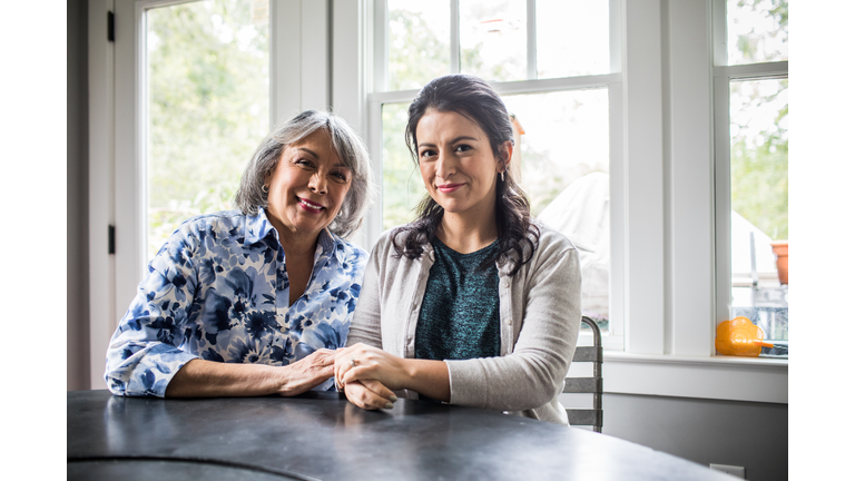 Portrait of senior woman and adult daughter in kitchen