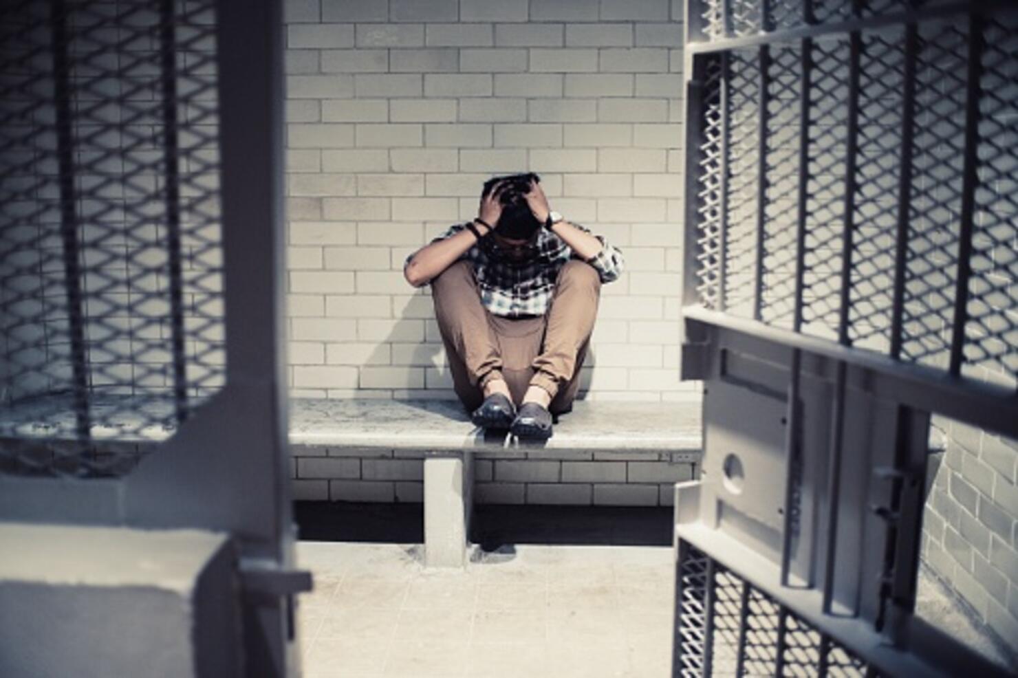 Full Length Of Man Sitting On Seat At Prison