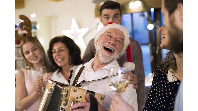 Senior man playing accordion for happy family at Christmas