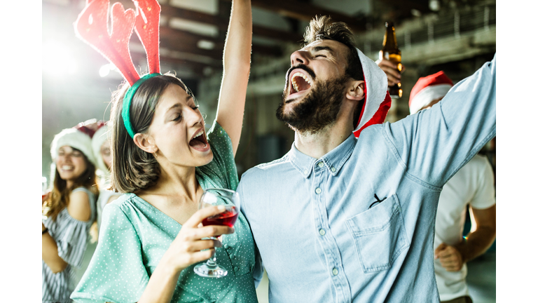 Happy couple having fun while singing on Christmas party.