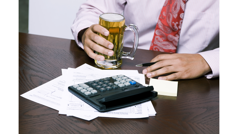 businessman doing his taxes and drinking a beer