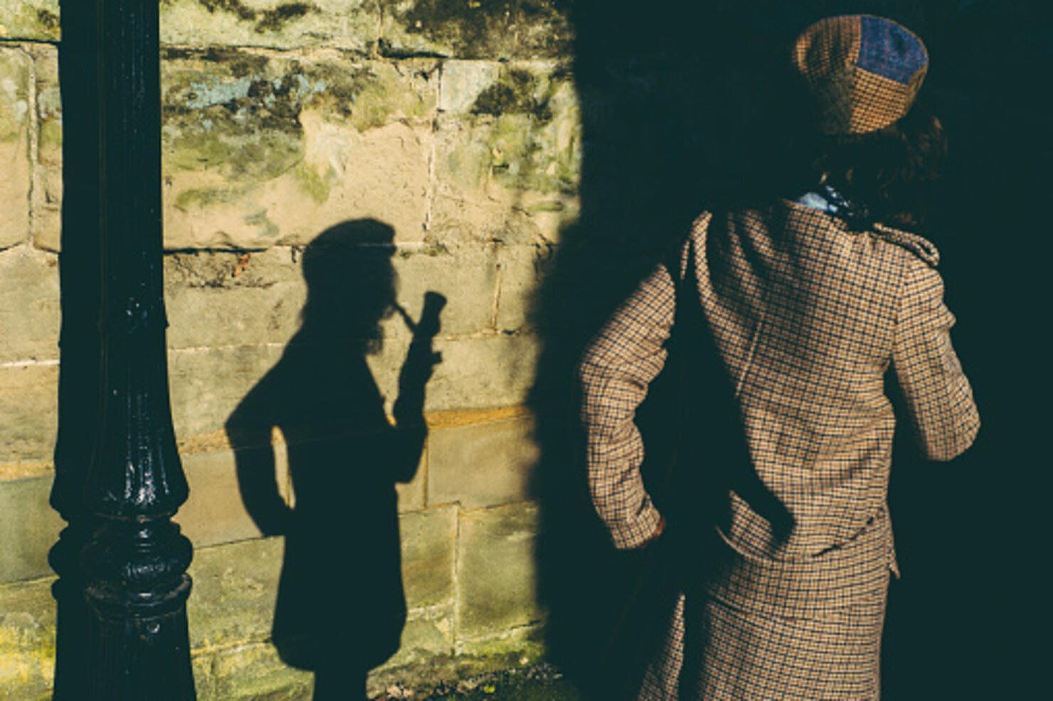 Elegant lady smoking pipe projecting shadow of herself on wall