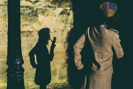 Elegant lady smoking pipe projecting shadow of herself on wall